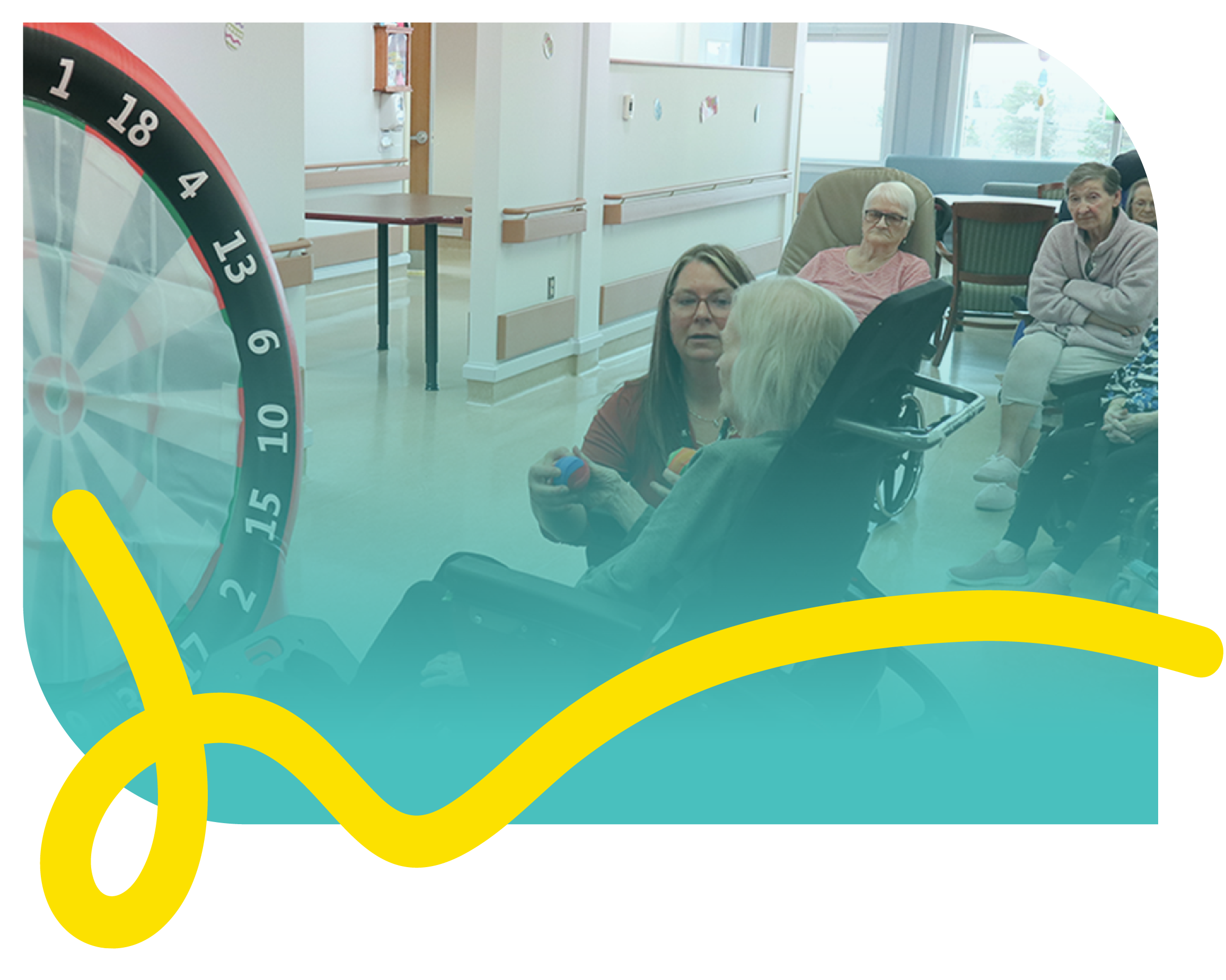 A long-term care resident sits in front of a recreational game assisted by a care provider.