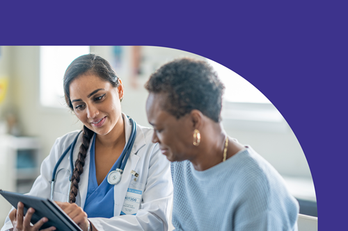 A female healthcare professional explaining a care plan to another female patient while both are looking at a tablet.