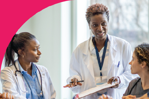 A diverse group of nursing students sit around a conference table as they listen attentively to their lead doctor. The lead doctor holds a clip board as they lead a discussion around patient safety.