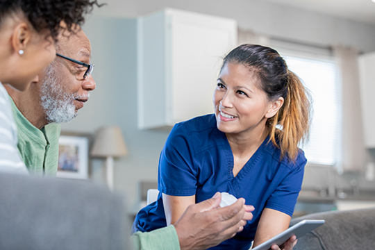 Female nurse smiling at patient as they discuss medication.