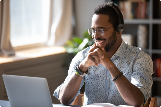 Smiling person looks at laptop computer.