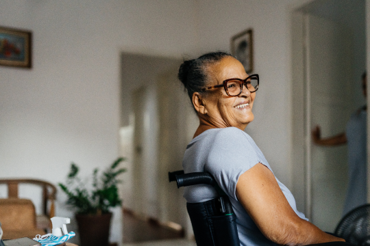 An older adult sits in a wheelchair in their home.